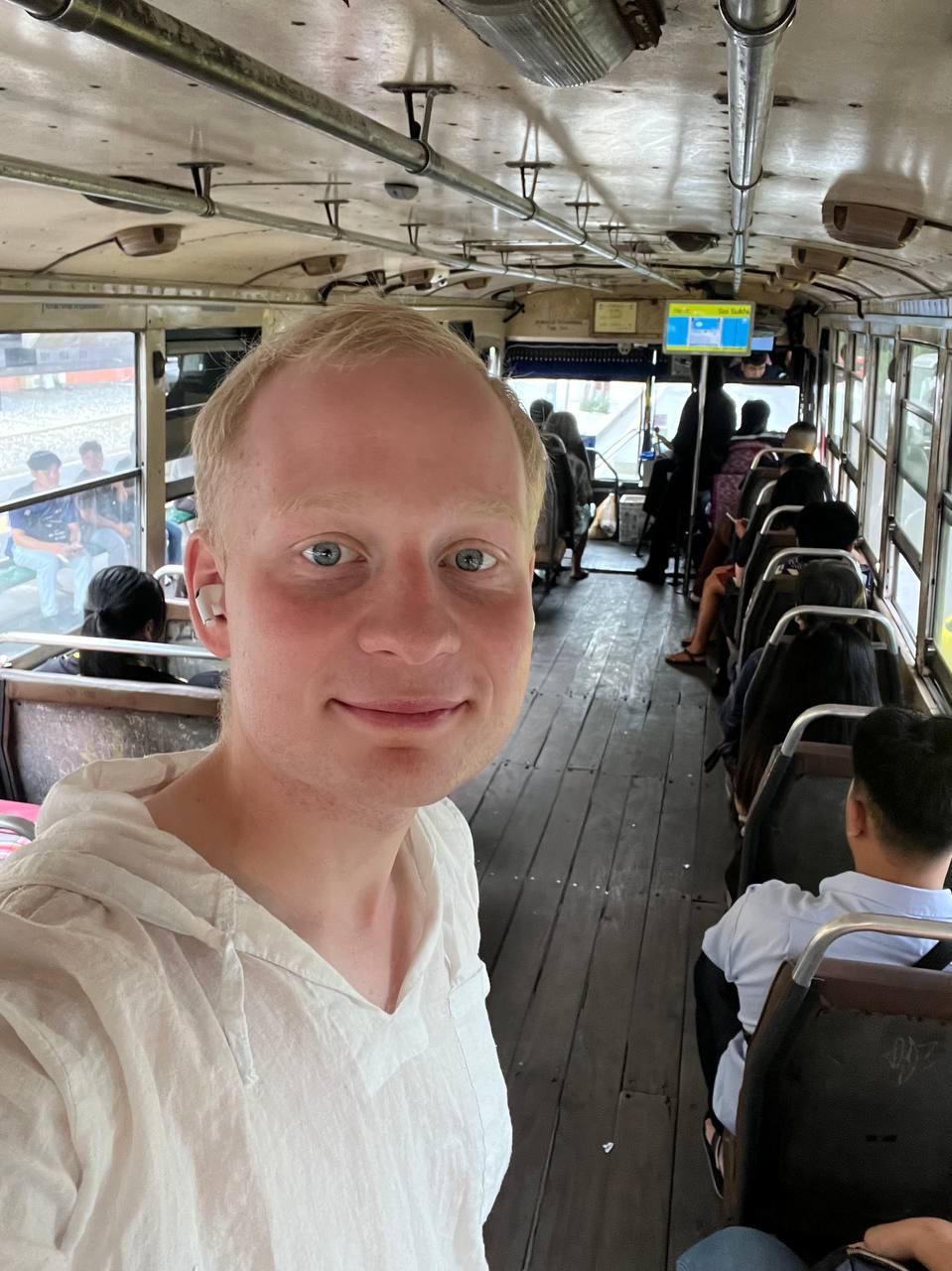 Inside an old Bangkok bus — wooden floor, ceiling fans, 8 baht
