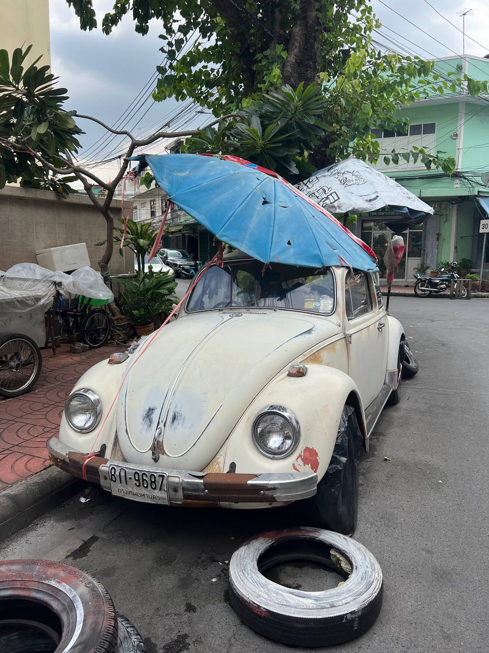 A vintage VW Beetle repurposed as a street stall in Bangkok — the kind of scene that doesn't make it into any tourist guide