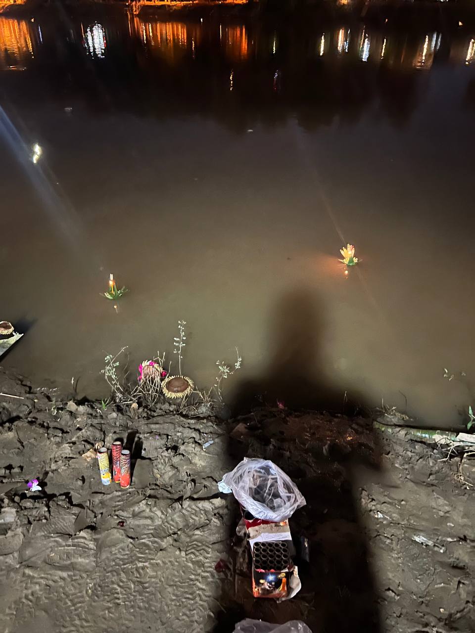 Krathongs floating on the river at night — each carries a candle and a wish